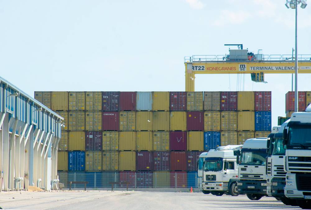 contenedor logístico en puerto iluminado con grúas y carga marítima al atardecer